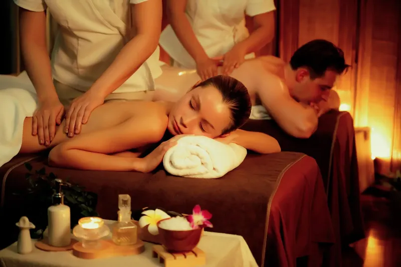 Two clients receiving a relaxation massage in a candlelit spa room